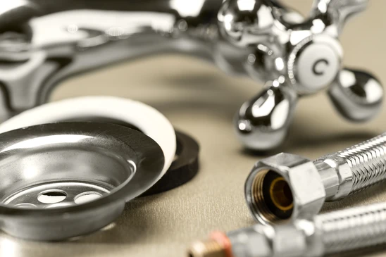 Scène d'atelier de plomberie avec évier en inox, robinet chromé et flexible de raccordement